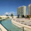 Fotografía inmobiliaria de amenidades: alberca estilo resort con las torres del desarrollo al fondo